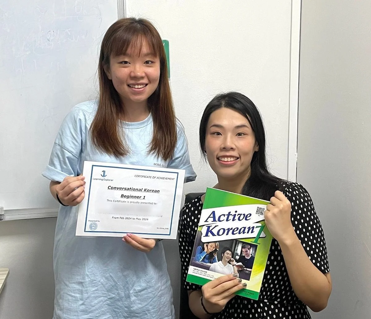 A student with her Beginner 1 certificate and the Active Korean coursebook